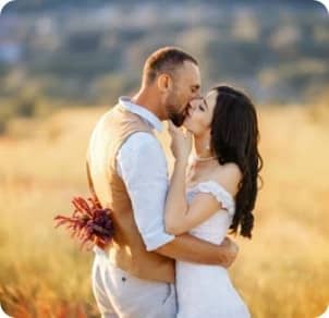 Un couple s'embrassant dans un pré, la femme porte un bouquet de fleur dans sa main