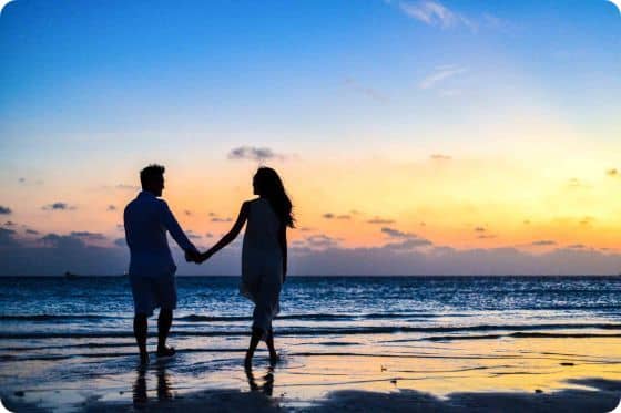Couple d'amoureux se regardant et se tenant la main sur la plage