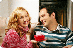 Couple souriant, avec la femme tenant à sa main un cadeau pour son homme