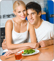 Couple souriant devant une table avec une assiette et un verre à vin rosé