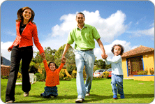 Image d'une famille : père et mère prenant par la main chacun un enfant, en promenade dans le jardin
