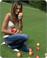 Femme dans un jardin, entouré de pommes au sol, tenant dans ses mains des pommes