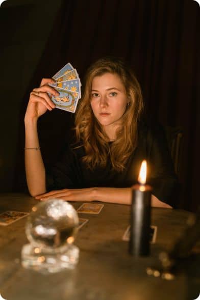 Une tarologue avec ses cartes devant une boule de crystal
