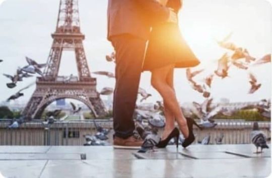 Couple s'embrassant sur l'esplanade du Trocadéro, avec la tour Eiffel en fond, entourés de pigeons volants