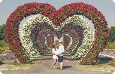 Couple devant des rangées de fleurs en forme de coeur