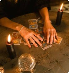 Image des mains d'une tarologue avec ses cartes et sa boule de cristal