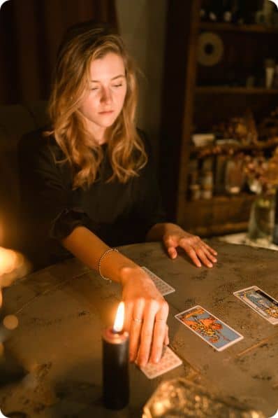 Une tarologue tirant des cartes, dans l'obscurité illuminée par une bougie